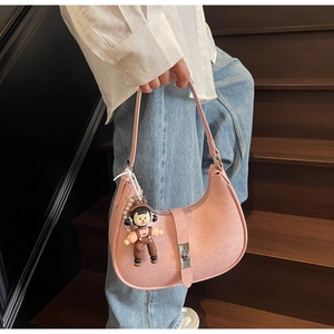 Close-up of pink textured leather hobo bag with silver clasp and girl doll pendant