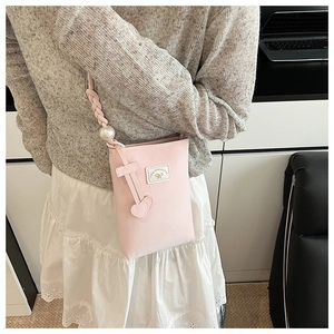 Detail of pink crossbody phone bag featuring a pearl-embellished strap and heart charm