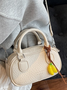 Minimalist cream boston crossbody bag with pebble leather texture and banana charm