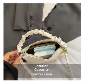 Détails de l'intérieur du sac à main plissé blanc montrant l'espace pour maquillage