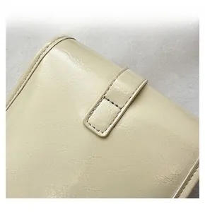 Macro detail of creamy white leather handbag showing precise stitching and litchi texture