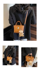 Détail d'un mini cabas en cuir marron avec motifs monogrammes et pendentif ours mignon