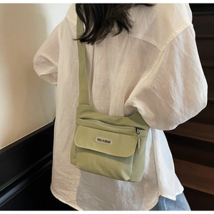 Dettaglio della borsa a tracolla in nylon verde chiaro impermeabile con logo sulla tracolla