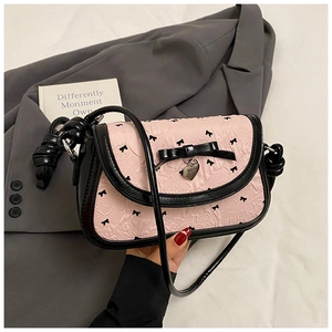 Detailed shot of pink shoulder bag with black bow print and silver heart charm pendant