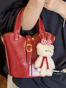 Sac seau en cuir verni rouge chic avec finition brillante et joli charm en ours peluche