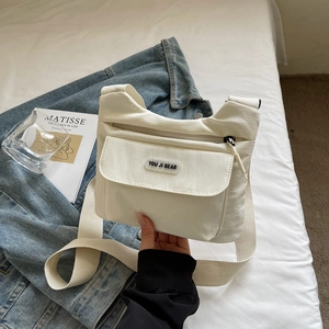 Dettaglio della borsa a tracolla minimalista in nylon crema con tasca e tracolla in tessuto