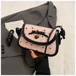 Detail of pink jacquard fabric with black bow print and a heart metal charm on the bag