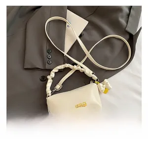 Détail du sac polochon en cuir PU blanc avec poignée à froufrous et charm nœud mignon