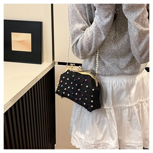 Dettaglio di una borsa da sera vintage con perle colorate e una lunga catena di perle