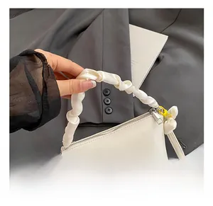 Détail du sac polochon blanc crème avec poignée en satin plissé et serrure dorée