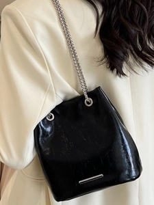 Large black glossy patent leather bucket bag with silver chain straps and metal detail