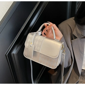 Detail of silver metallic handbag with diamond lattice texture and fashion logo tag