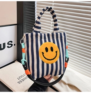 Détail du sac en toile rayé avec écusson smiley jaune et bandoulière colorée robuste