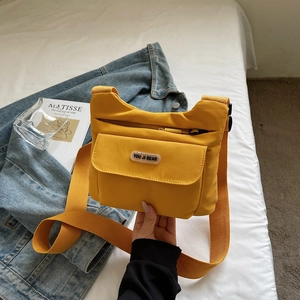 Dettaglio della borsa a tracolla in nylon giallo con tasca a patta e logo in stile casual