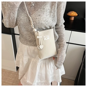 Chic beige mini phone bag featuring pearl-accented strap and golden heart charm detail