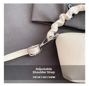 Détail d'un sac oreiller blanc avec fermoir argenté et bandoulière à volants