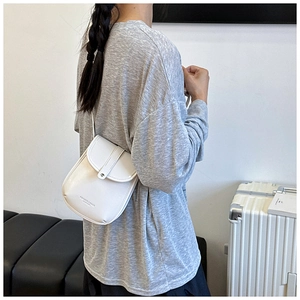 Detail of minimalist white leather crossbody phone bag with silver snap and shoulder strap