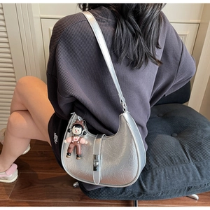 Detail of silver metallic dumpling bag with pleated texture and cartoon doll pendant