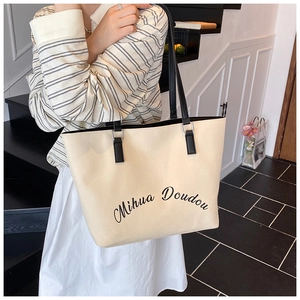 Détail du sac cabas minimaliste en toile beige avec anses noires et typographie artistique