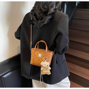 Détail du sac à main vintage marron avec motif d'ours et accessoire en peluche d'ours