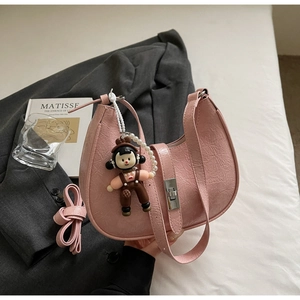 Close-up of pink crescent bag with textured leather, silver hardware and a pearl charm