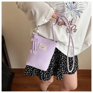 Detail of lavender mini phone bag with bow embroidery and a large white pearl pendant charm