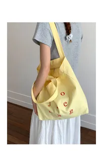 Macro shot of large canvas tote bag with red lettering and secure zipper closure