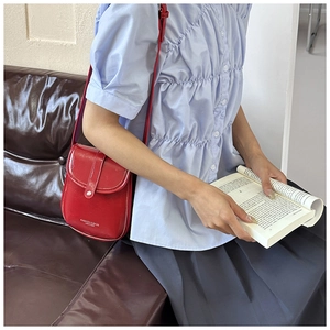 Detail view of red leather crossbody bag with silver button snap and fashion branding
