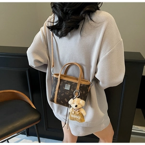 Détail d'un sac bandoulière marron vintage avec charm ours et imprimé monogramme