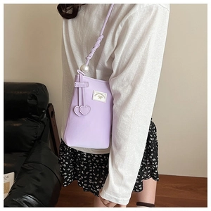 Detail of lavender mini crossbody bag with woven strap, pearl accent and heart pendants