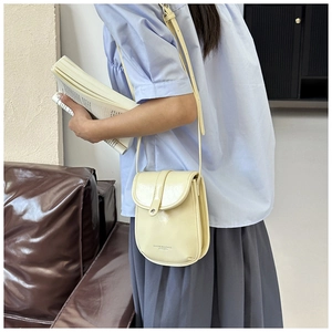 Detail of a creamy yellow PU leather phone bag with a flap closure and metal buckle