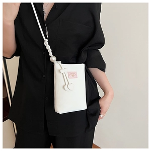 White PU phone bag with woven pearl strap and heart pendant detail on a black shirt