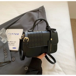 Detail shot of black leather quilted crossbody bag with golden buckle and fashion tag