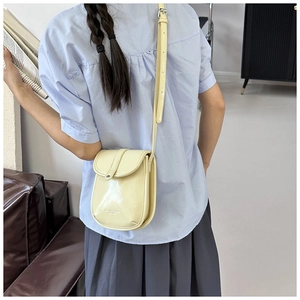 Pale yellow crossbody phone bag in glossy PU leather shown in a lifestyle back view
