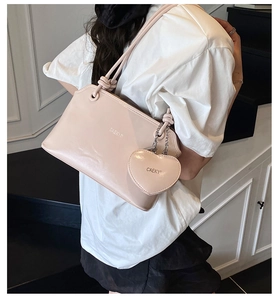 Pink minimalist underarm bag with heart-shaped charm and knotted shoulder strap