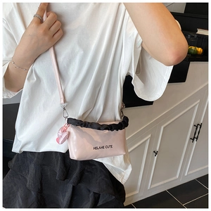 Détail du sac polochon rose brillant avec bordure à volants noirs et breloque en cœur