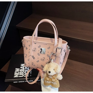 Sac rose à motifs ours, logo métallique et breloque chiot en peluche sur des marches