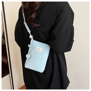 Detail of light blue crossbody phone bag with pearl strap and heart pendants