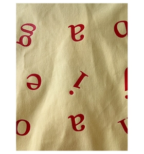 Close-up of beige canvas material with red letter print and premium twill texture