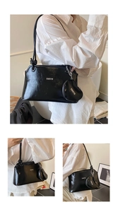 Detail view of the black glossy shoulder bag featuring the CAEKYD logo and heart charm