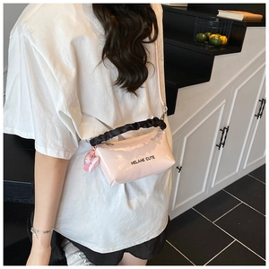 Détail du sac polochon en cuir verni rose avec poignée froncée noire et breloque en cœur