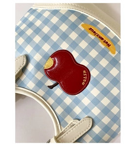 Detail of blue and white checkered bag featuring a red apple patch and embroidery