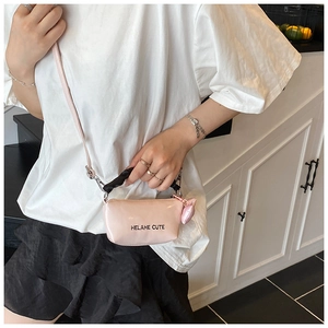 Détail du mini sac polochon rose clair avec poignée noire et breloque oreille de chat