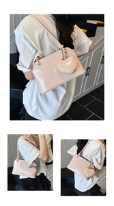 Detailed view of a glossy light pink underarm bag featuring a heart-shaped charm and logo