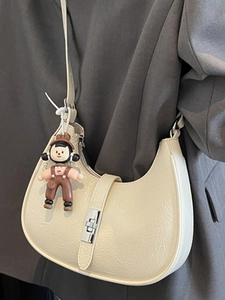 Chic cream dumpling hobo bag with pleated texture and cute doll charm accessory