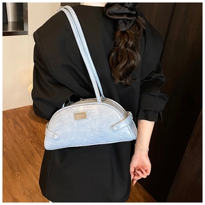 Detail of light blue faux leather shoulder bag with crocodile pattern and metal logo
