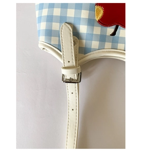 Close-up of blue plaid fabric detail with apple embroidery and adjustable leather strap