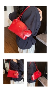 Detail of a shiny red underarm bag with an extra heart-shaped pouch and silver logo