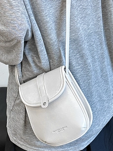 Minimalist light grey leather crossbody flap bag with textured finish and shoulder strap