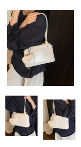 Detailed view of white minimalist underarm bag with polished finish and heart charm